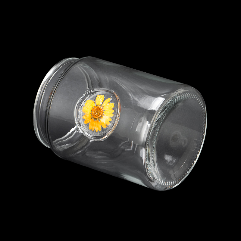 glass candle jar with dry flower attached in glass wall