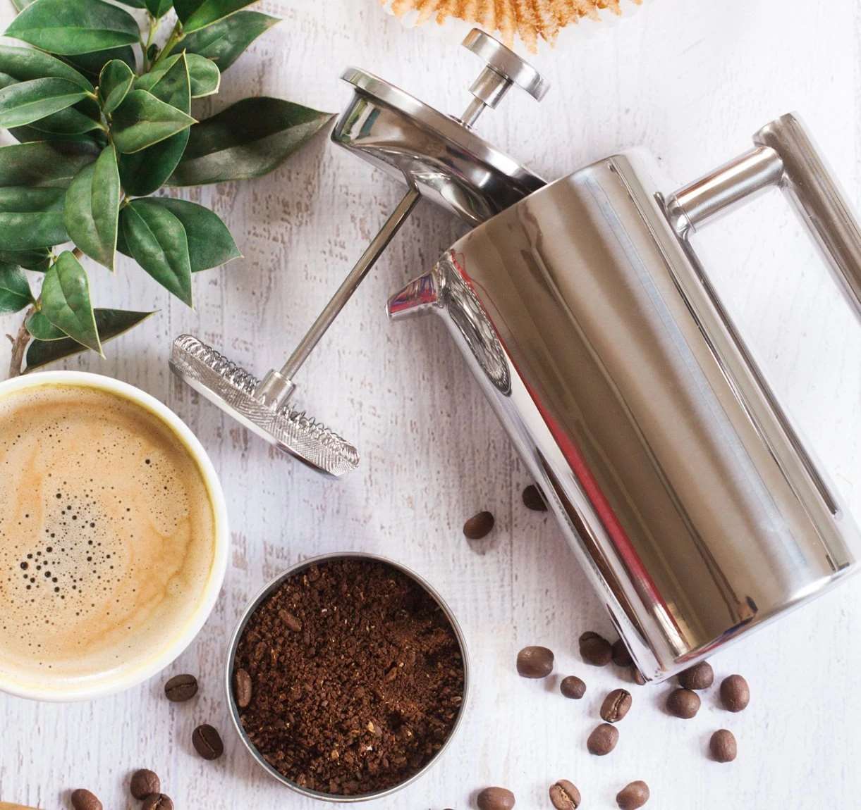 Coarse-ground coffee beside a stainless steel French press, showing a suitable grind size for French press brewing.
